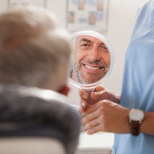Man bekijkt het resultaat in een spiegel en lacht aan de hand van orthodontie