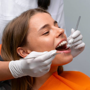 Vrouw in een oranje shirt krijgt controle voor een gaatje in haar tand of kies