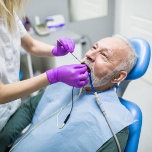 Oudere man met baard krijgt een parodontologie behandeling bij parodontitis